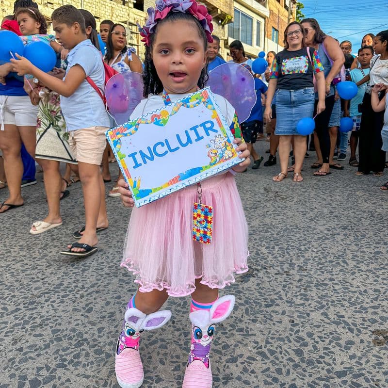 Criança com placa INCLUIR em caminhada pela inclusão em Escada